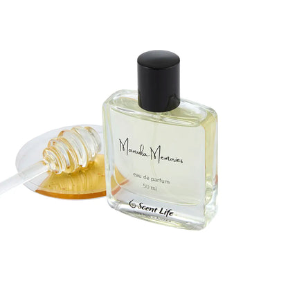 A 50 ml bottle of Scent Life's Manuka Memories eau de parfum rests next to a honey dipper, glistening with golden sweetness. The bottle's rectangular design, complete with a black cap and sophisticated text, embodies the honeyed essence of the Manuka scent, highlighting its captivating fragrance.