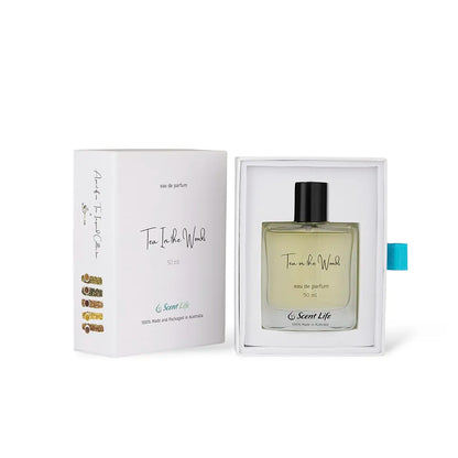 A bottle of Scent Life's Tea in the Woods eau de parfum, celebrated for its enduring scent, is presented in an open box. The packaging features a white box adorned with gold lettering and a teal pull-tab, underscoring the sophisticated and minimalist design of this refined perfume.